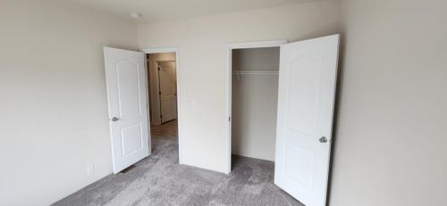 An empty room with two doors and a carpet.