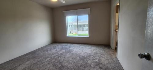 An empty room with carpet and a ceiling fan.