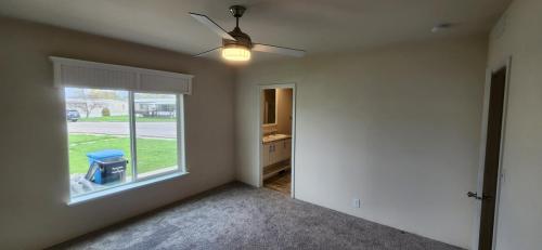 An empty room with a ceiling fan and carpet.