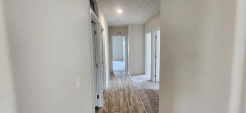 A hallway with a wooden floor and white walls.