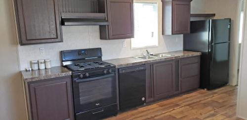 A kitchen with black appliances and wood floors.