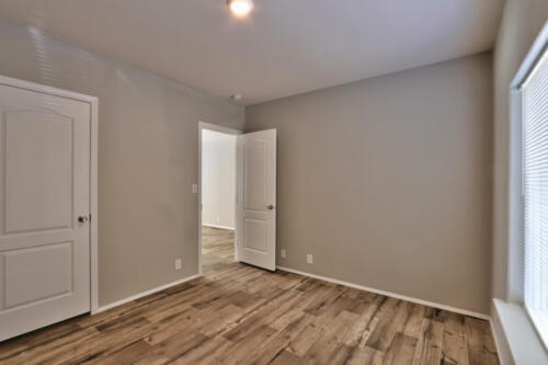 An empty room with hardwood floors and white doors.