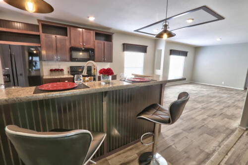 A kitchen with bar stools and hardwood floors.