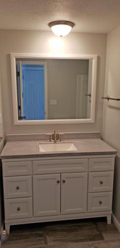 A bathroom with a white vanity and mirror.