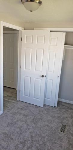 An empty room with white doors and a closet.