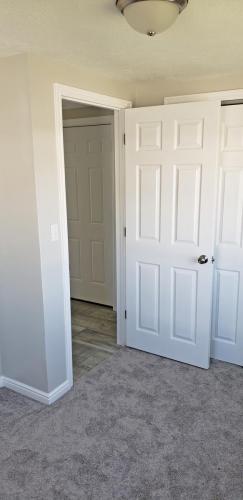 An empty room with white doors and carpet.