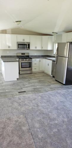 An empty kitchen with gray carpet and stainless steel appliances.